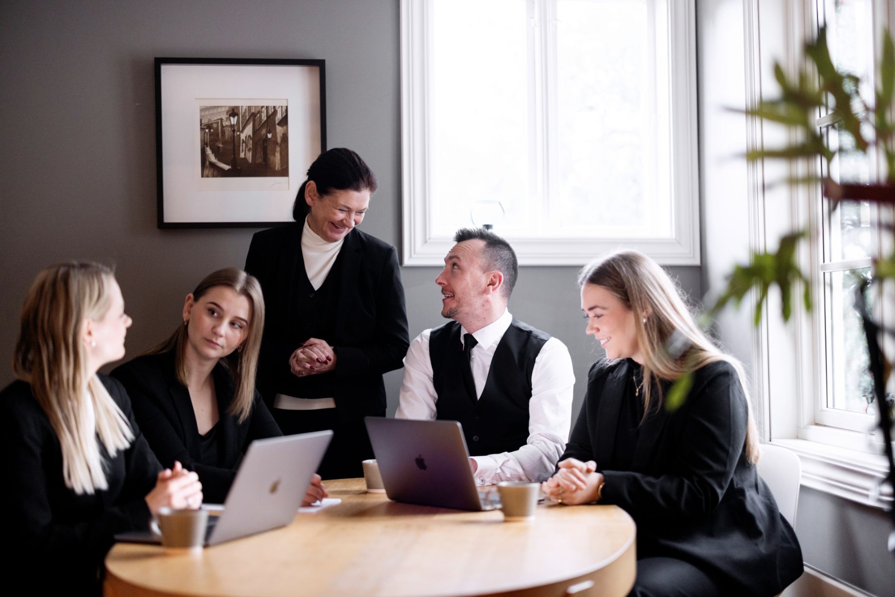 Et team av jurister har et uformelt møte rundt et bord med bærbare PC-er.